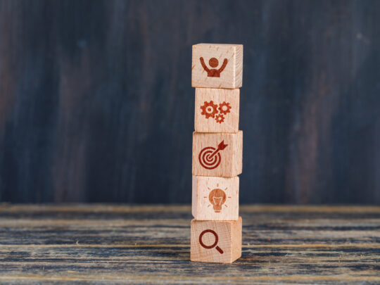 Business strategy concept with wooden cubes on wooden and grunge background side view.